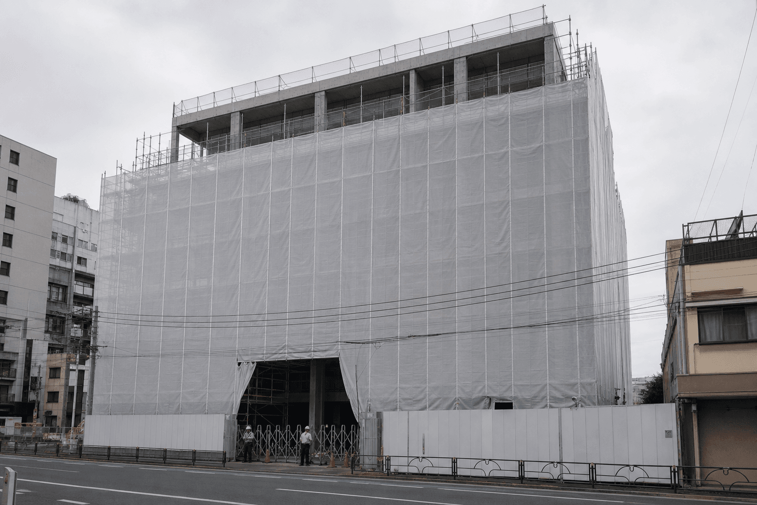 足場と白い養生シートに覆われた建築工事現場